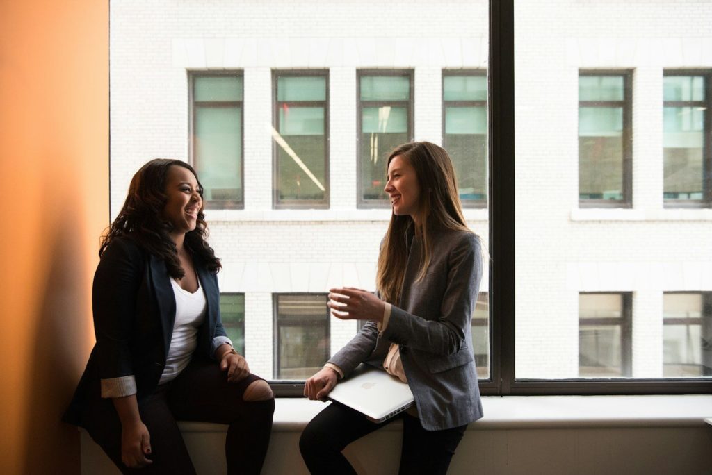 Two colleagues laughing by a window